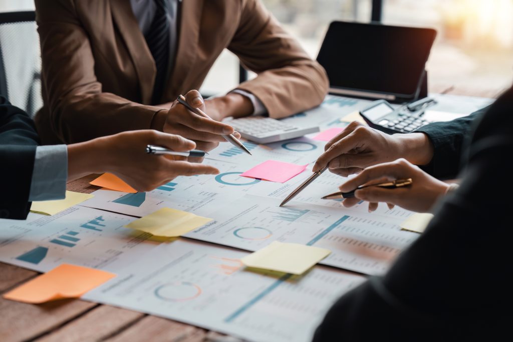 Équipe analysant des graphiques financiers en réunion, page À propos du site Fiducia Management à Luxembourg